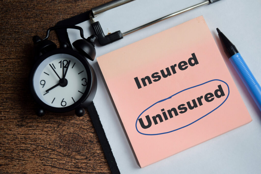 Concept of uninsured blue circle write on sticky notes isolated on Wooden Table.