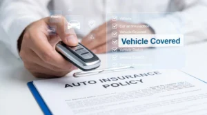 Person holding car key over auto insurance policy document on table with checklist